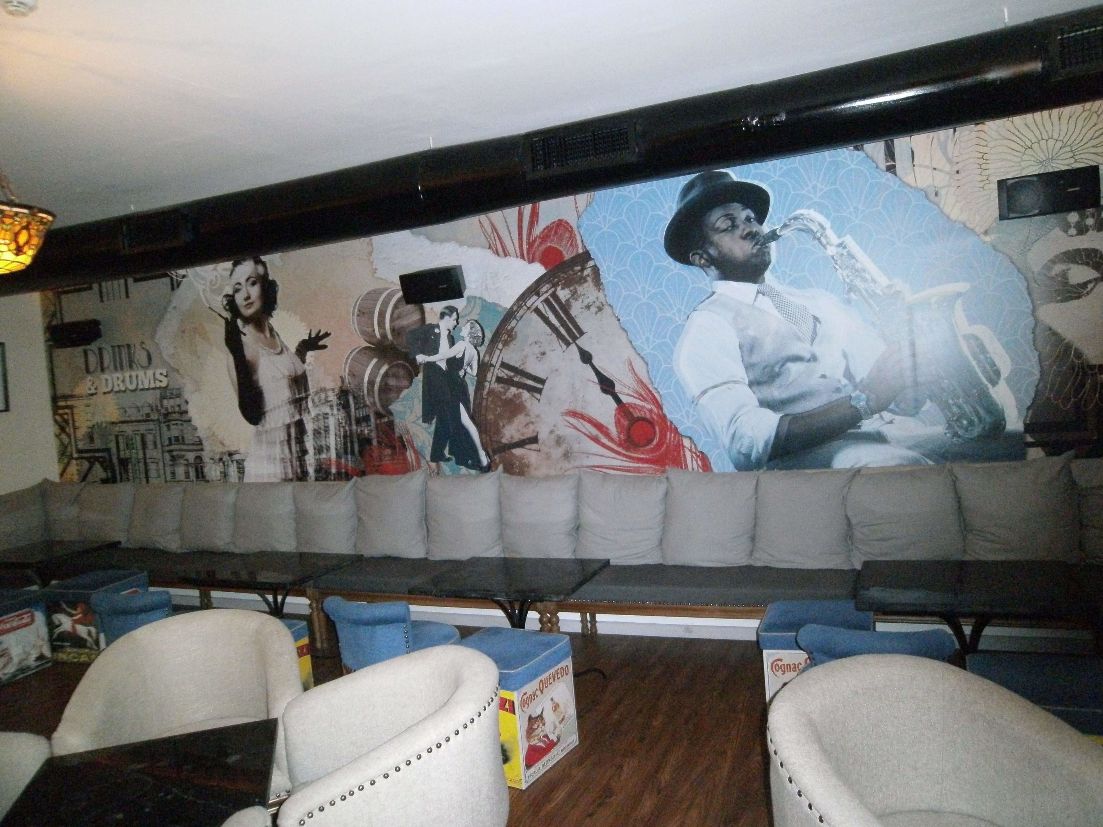 A restaurant with a mural, cushioned seating, and tables.