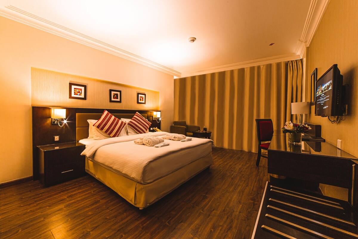A hotel room with a large bed, bedside tables, a desk, and a chair.