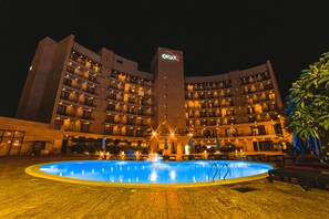 A hotel with a swimming pool, multiple balconies, and a well-lit facade. - Oryx Aqaba (Aqaba)