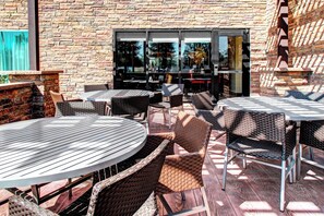 Una terrazza esterna con mobili in vimini, un muro in mattoni e una porta in vetro che dà sull'interno.