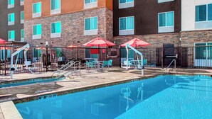 A hotel pool area with a clear pool, lounge chairs, and umbrellas. - Towneplace Suites Bakersfield West (Bakersfield)