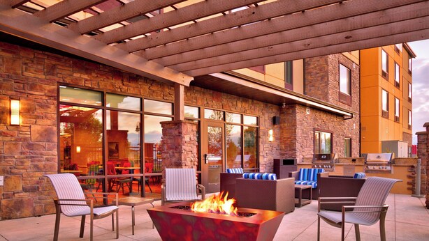 An outdoor patio with stone walls, a fire feature, and seating. - Towneplace Suites Salt Lake City-West Valley (West Valley City)