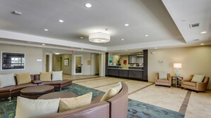 A spacious lobby with a large seating area, a reception desk, and a view of the kitchen area.