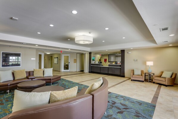A spacious lobby with a large seating area, a reception desk, and a view of the kitchen area.