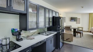 A modern kitchen with a built-in stove, a coffee maker, and a refrigerator.