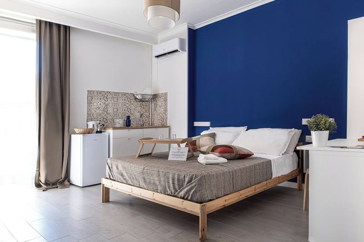 Une chambre à coucher moderne avec un lit, une table de chevet et un petit bureau.