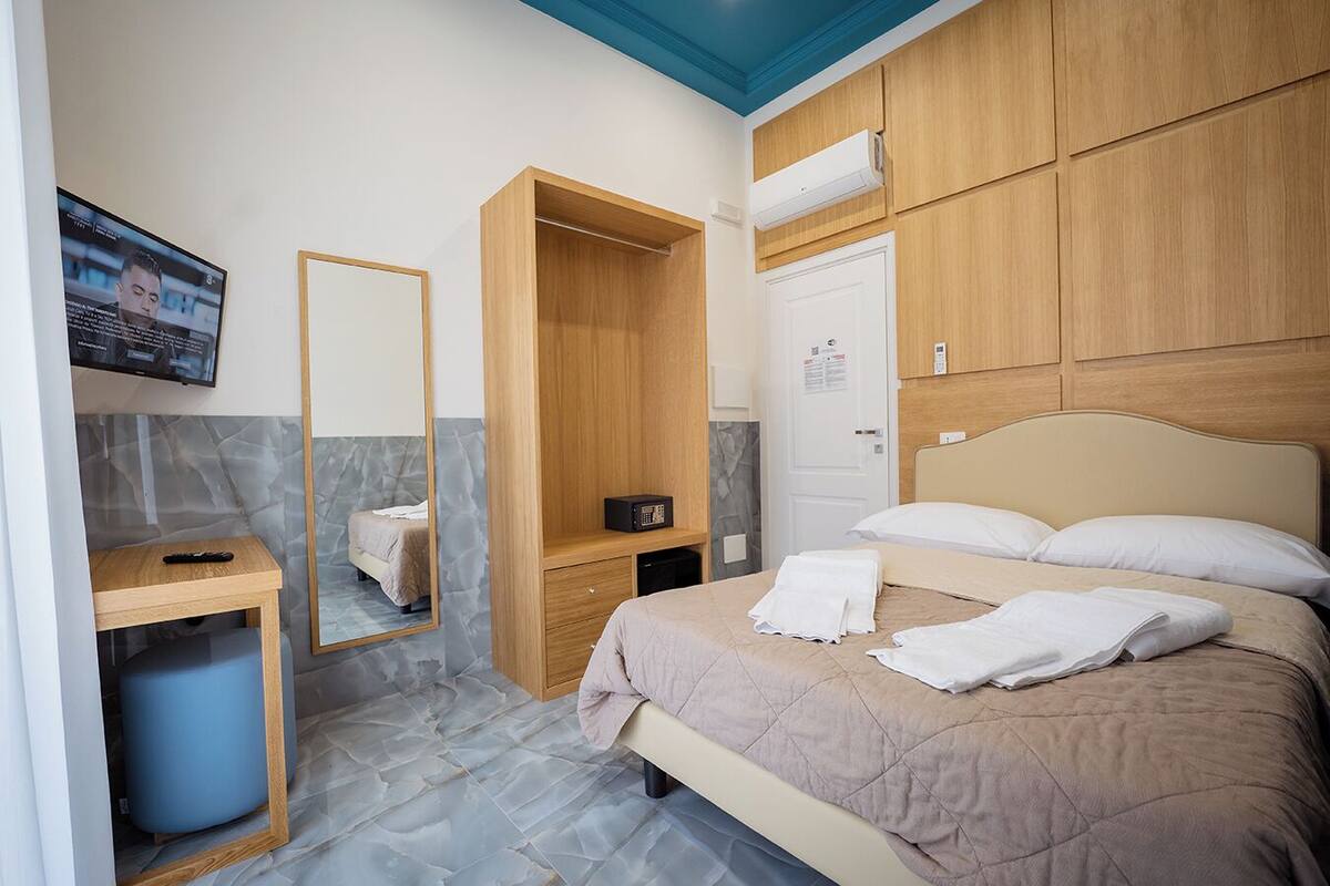 Une chambre d’hôtel comprenant un lit, une table de chevet, un miroir, une armoire et un téléviseur.