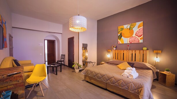 A modern bedroom with a large bed, a yellow chair, a desk, and a dining area. - B&B Le 4 Stagioni by ClaPa Group Dislocated Hospitality (Naples)