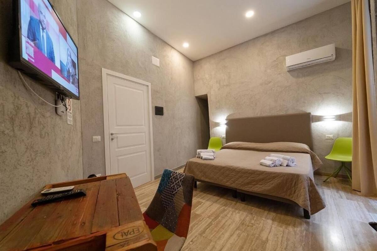 Une chambre d’hôtel comprenant un lit, un bureau avec une chaise, un téléviseur fixé au mur et un appareil de climatisation.