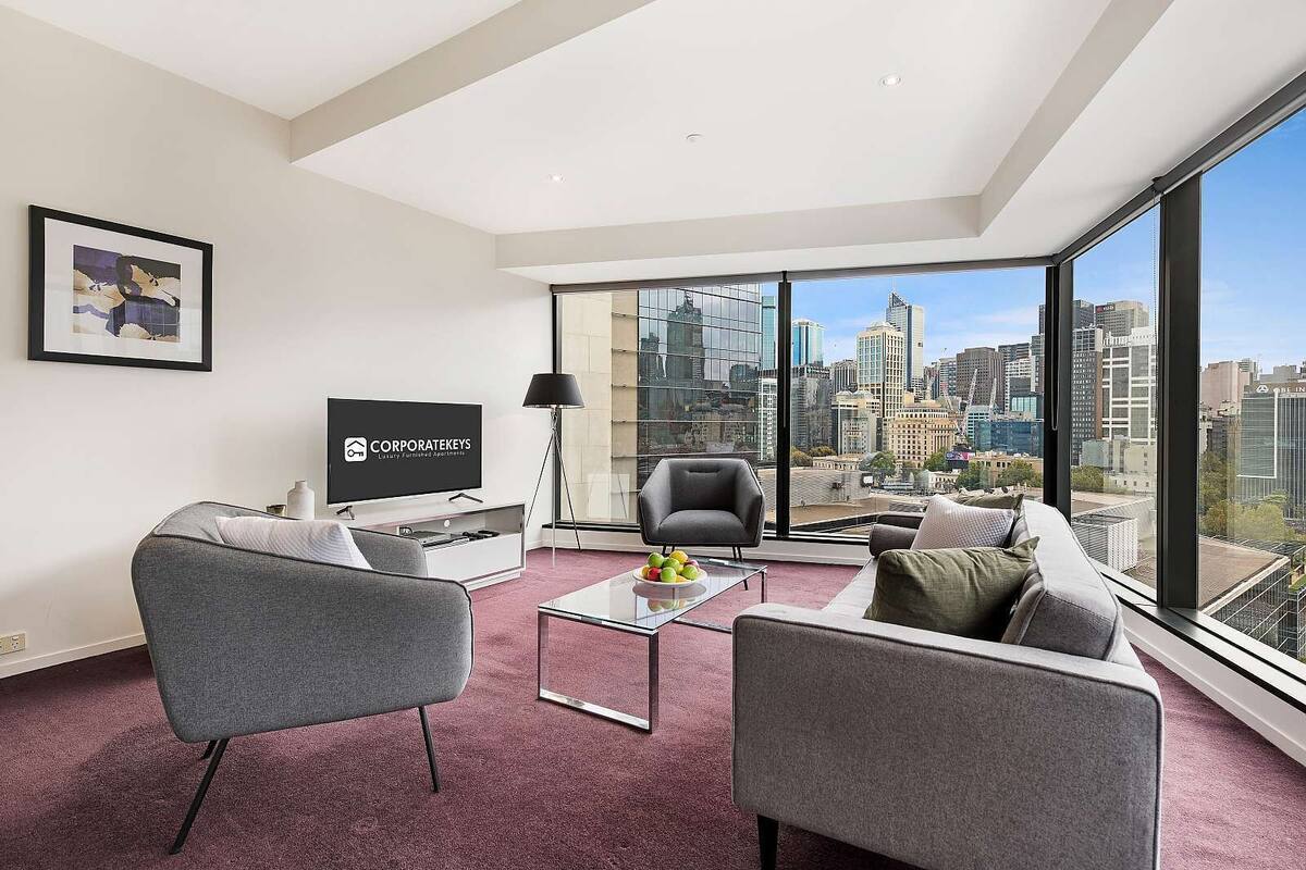 A modern living room with a city view, a flat-screen TV, and a large window.