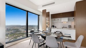 A modern dining area with a panoramic city view, a glass table, and contemporary chairs. - Southbank Apartments - Eureka Tower (Southbank)