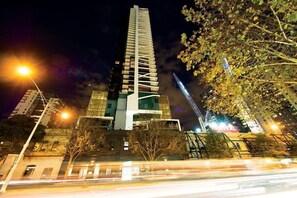 A modern high-rise building with a unique architectural design, featuring a central tower and multiple balconies.