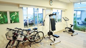 Une salle de sport équipée de vélos d’exercice, d’une machine de musculation et d’un appareil de type elliptique.