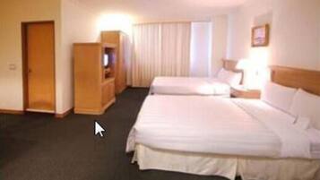 A hotel room with two beds, a TV, and a window with curtains.
