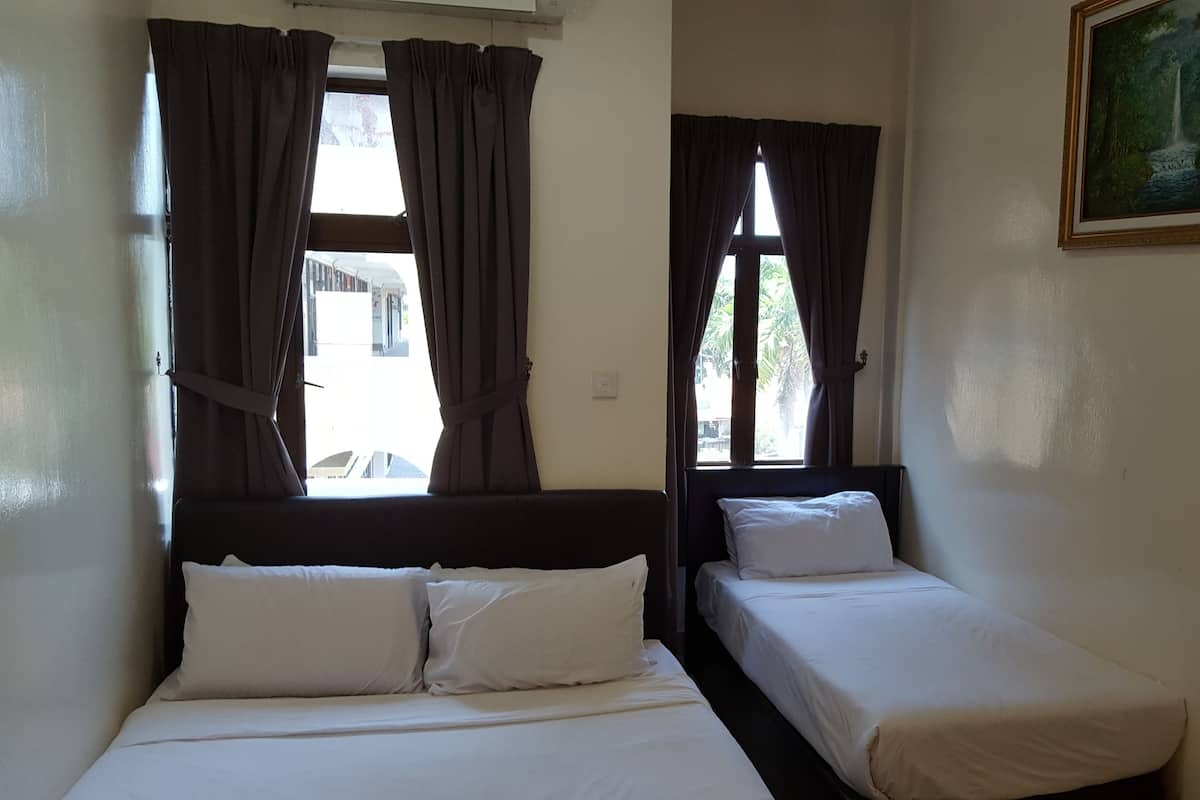 A room with two single beds, a painting on the wall, and windows with curtains.