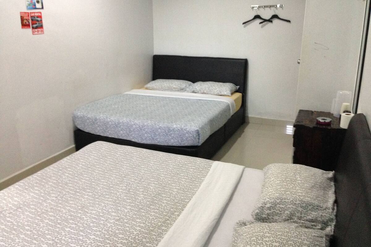 A bedroom with a bed, a bedside table, and a wall-mounted shelf.