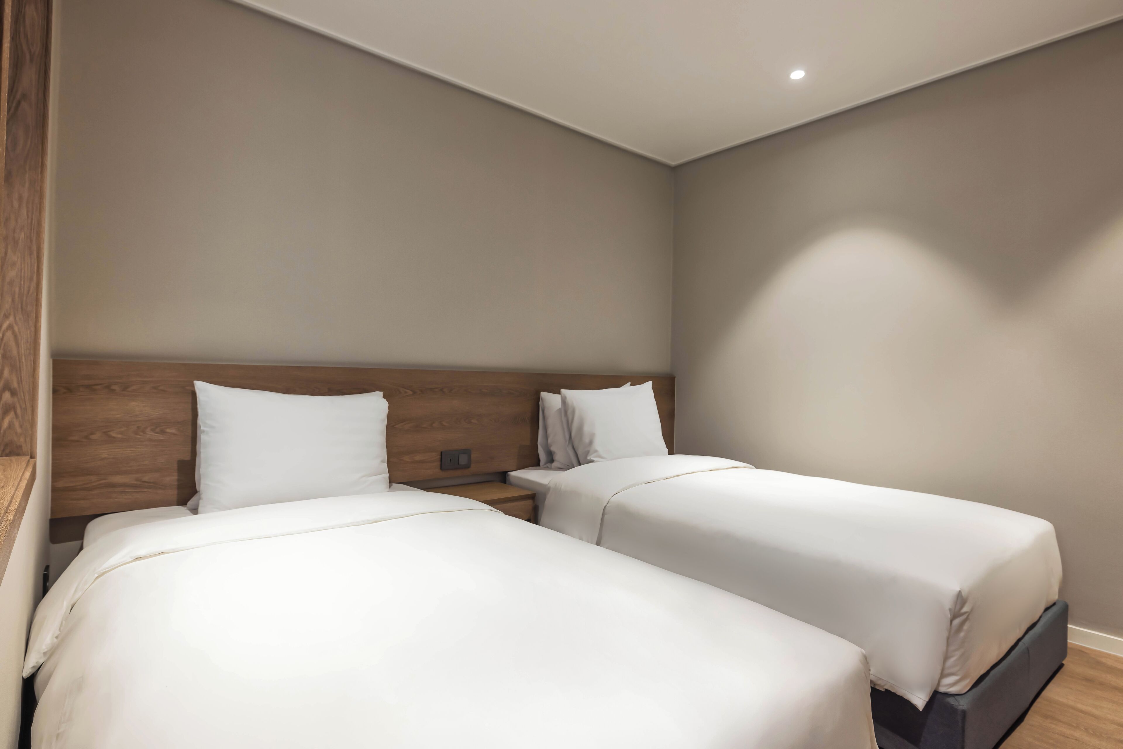 A hotel room with two beds, wooden headboards, and a neutral color scheme.