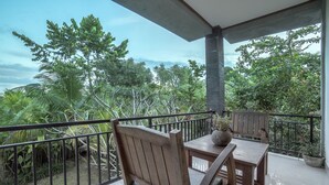 A balcony with wooden furniture and a view of lush greenery. - Gita Maha Hotel (Ubud)