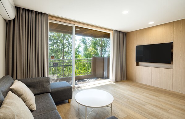 A modern living room with a grey sofa, a white coffee table, and a large TV mounted on the wall.