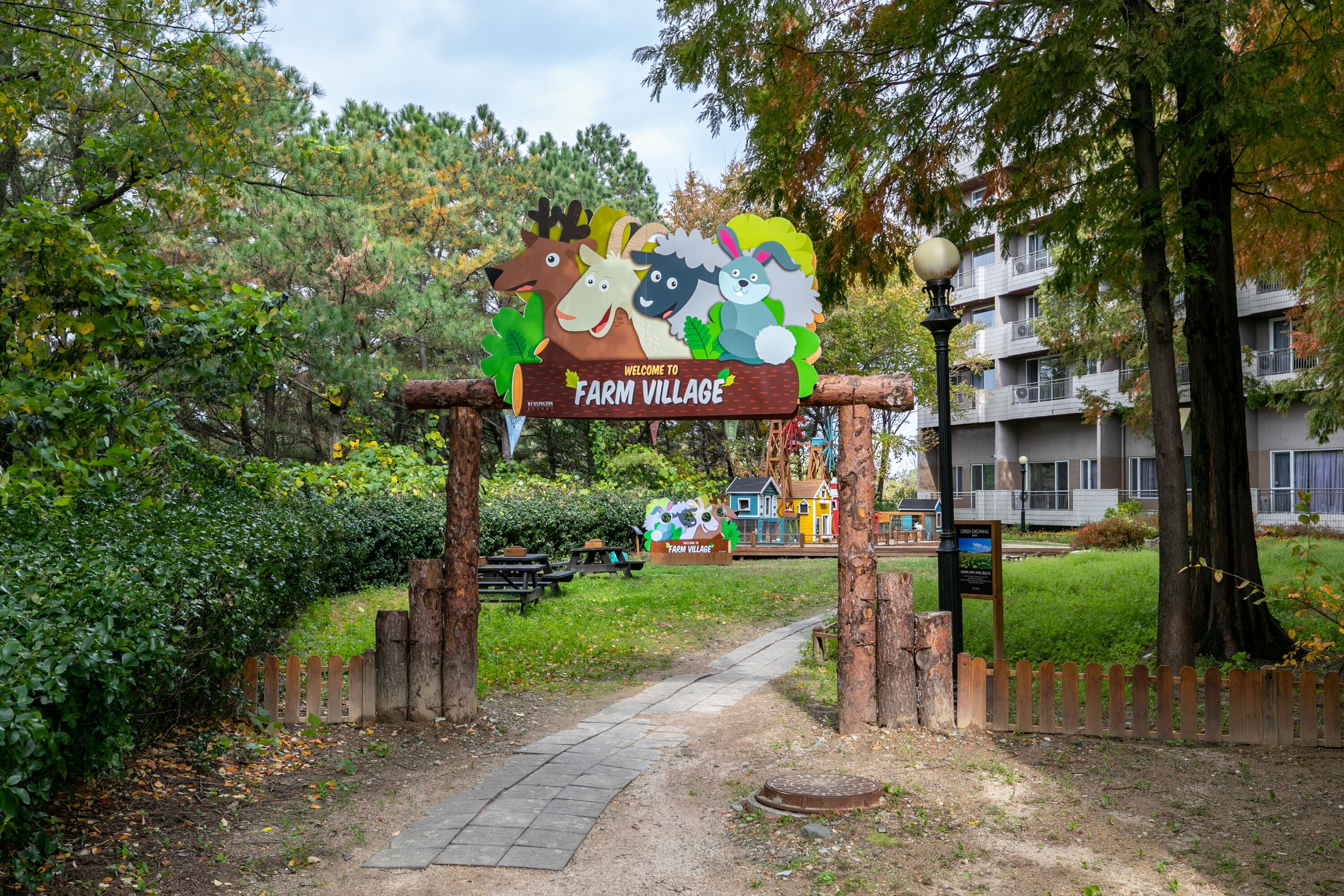 A wooden sign with cartoon animals welcoming visitors to Farm Village.