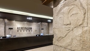 Ein Empfangstresen im KENSINGTON RESORT vor einer Wand aus Stein mit einer großen Steinschnitzerei.