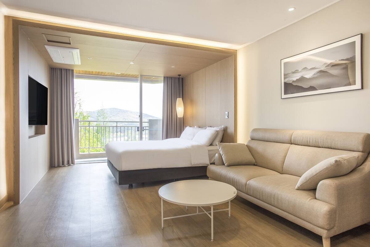 Ein modernes Hotelzimmer mit Bett, Sofa und kleinem Tisch.