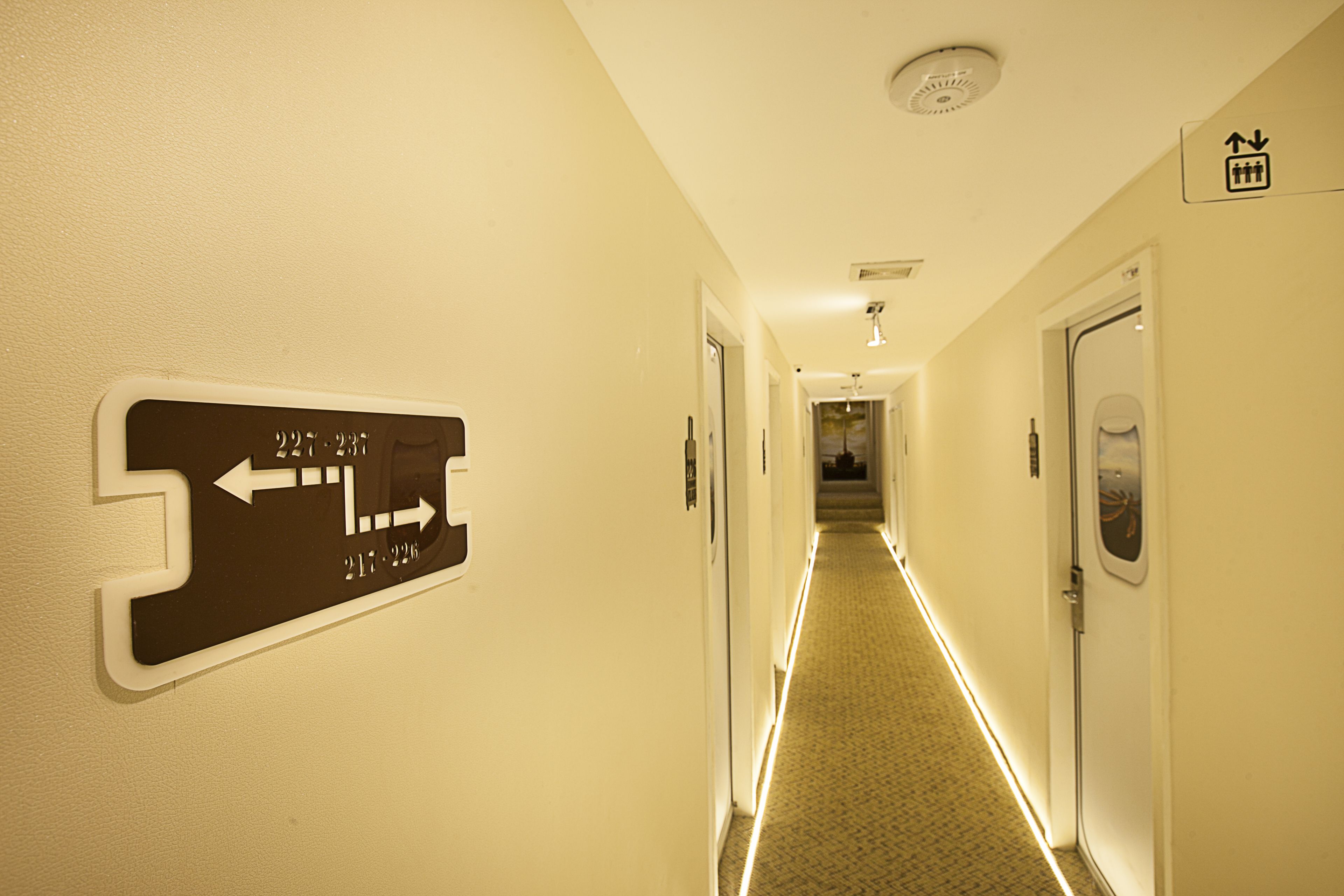 Ein Hotelgang mit Hinweisschildern, Türen und Teppichboden.