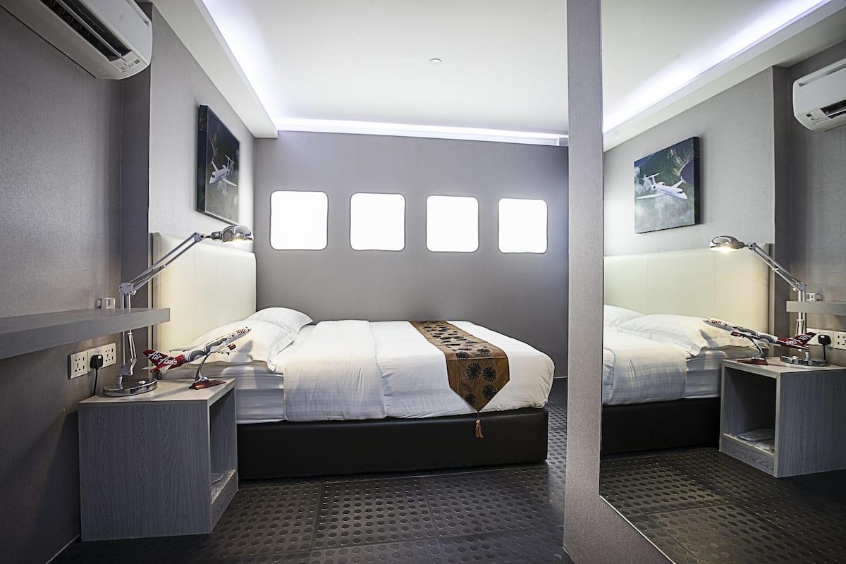 A modern hotel room with a large bed, bedside tables, and a wall-mounted air conditioning unit.