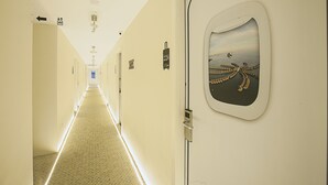 A hotel corridor with a carpeted floor, directional signs, and a door with a sea and octopus mural.