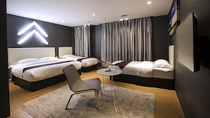 A modern hotel room with two beds, a small round table, and a chair.