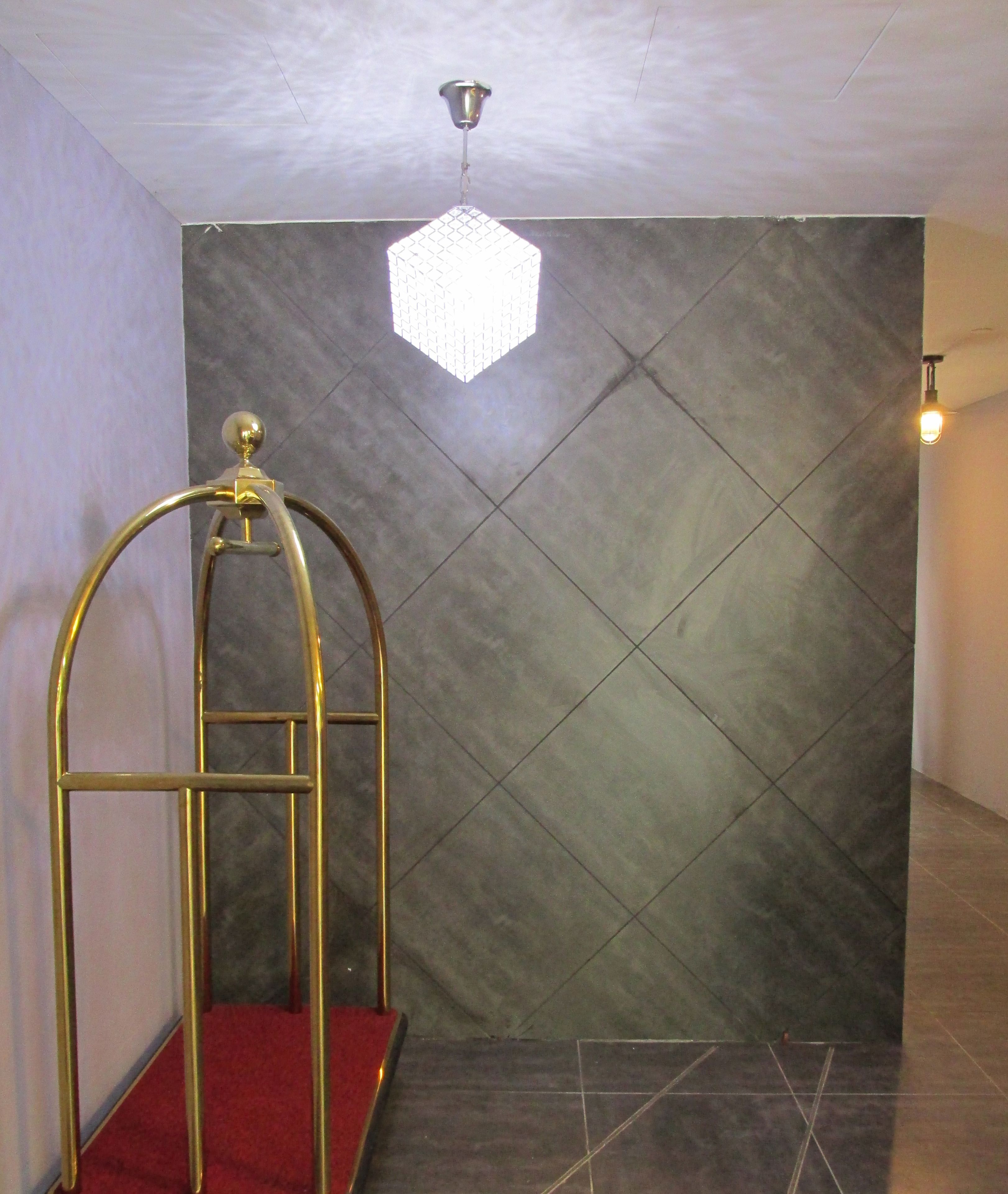A room with a red carpet, a geometric wall design, and a hanging light fixture.