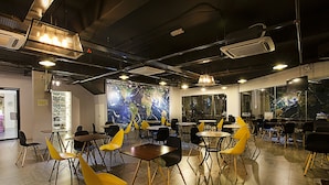 A modern dining area with tables and chairs, a large world map mural, and industrial-style lighting.