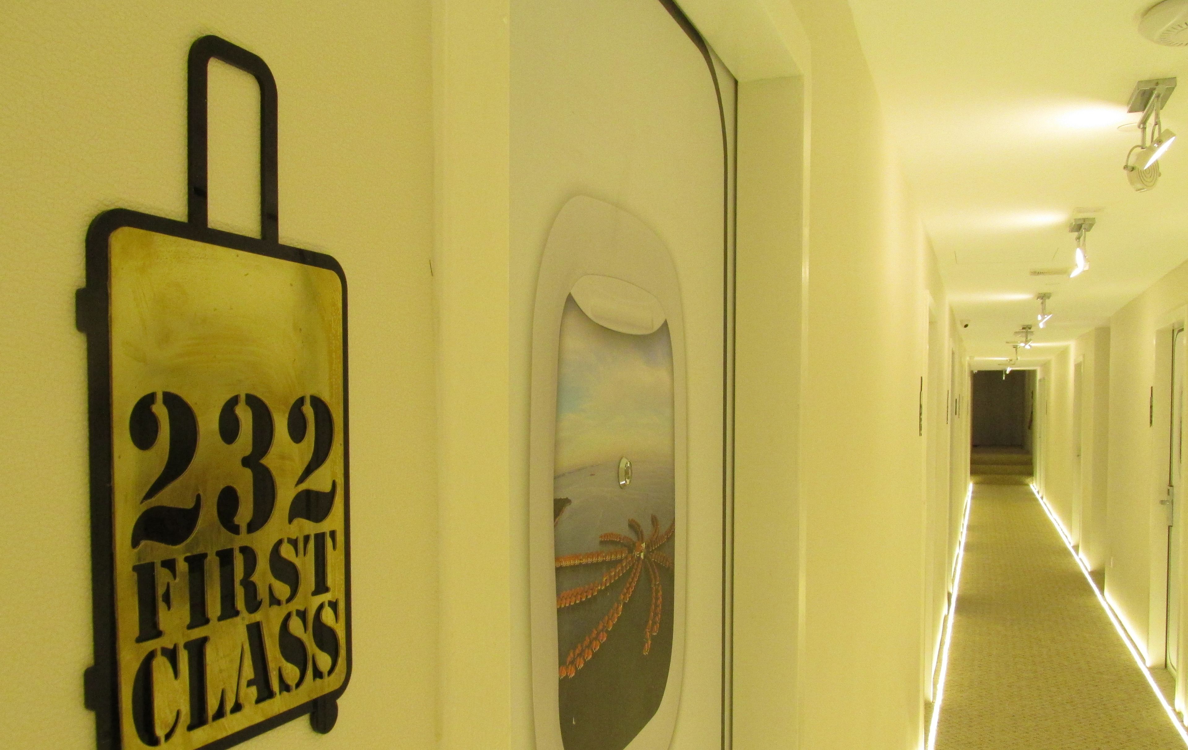 Un pasillo con un letrero que dice "232 First Class" y una puerta decorativa con una escena de playa.