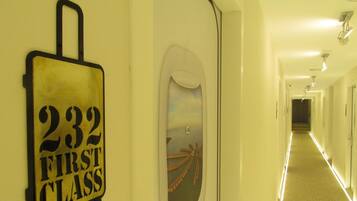 Un pasillo con un letrero que dice "232 First Class" y una puerta decorativa con una escena de playa.