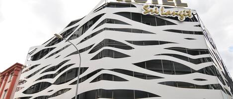 Un hotel moderno con una facciata ondulata caratteristica e un cartello 'HOTEL' ben visibile.