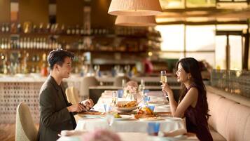 Una pareja cenando en un restaurante, con una barra de bar al fondo.