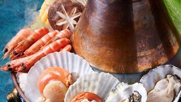 A decorative bowl with seafood, a copper pot, and a blue patterned plate.