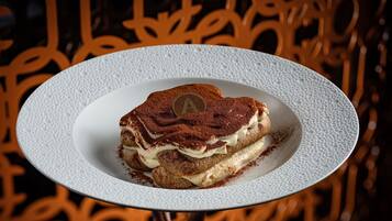 Un postre sobre un plato blanco con superficie texturizada, colocado sobre una mesa con superficie reflectante.
