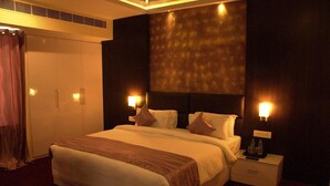 Une chambre d’hôtel avec un grand lit, des tables de chevet, une armoire et un mur orné d’un motif texturé.