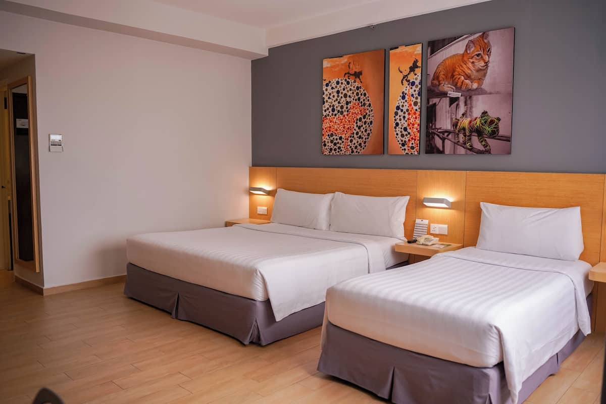 A hotel room with two beds, a wooden headboard, bedside lamps, and artwork on the wall.