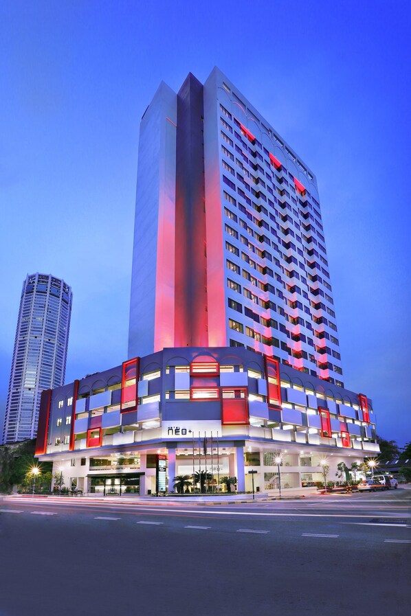 Un hotel moderno con varios pisos, un diseño vertical destacado y señalización iluminada.