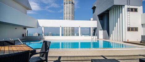 A rooftop pool area with a view of a tall building in the background.