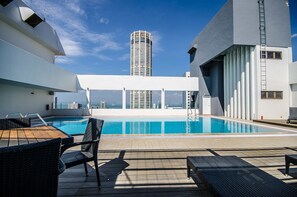 A rooftop pool area with a view of a tall building in the background. - Hotel NEO+ Penang by ASTON (George Town)