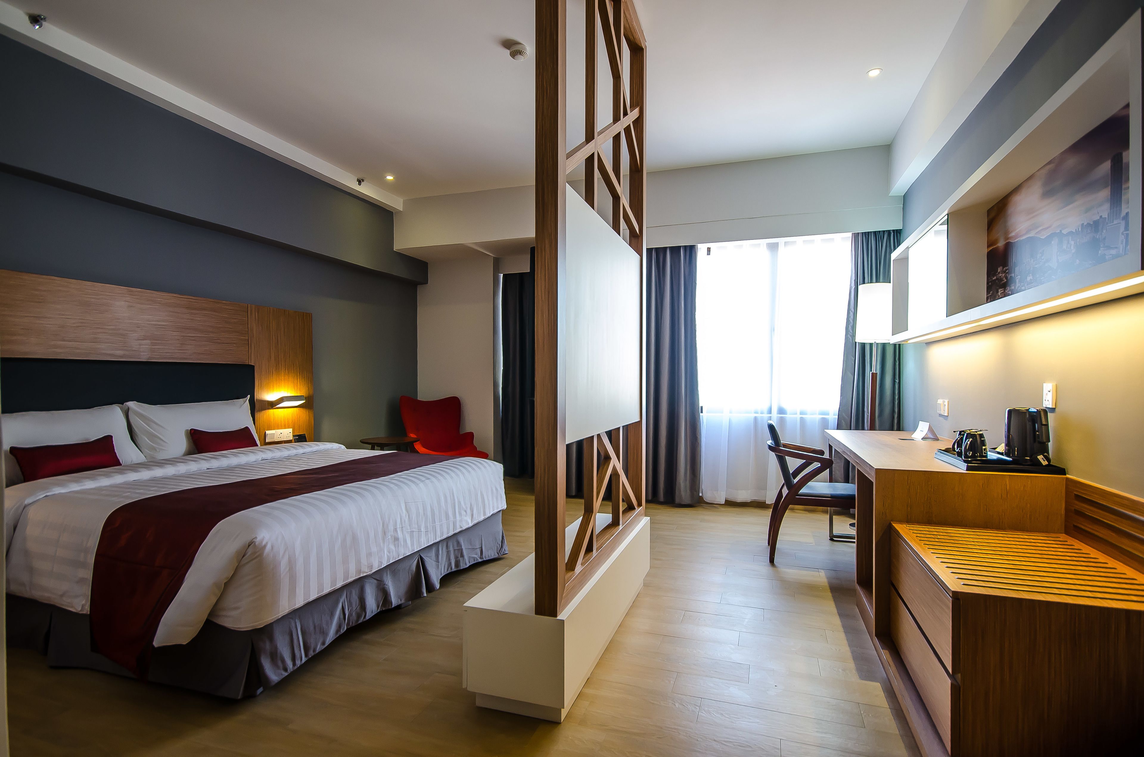 Una camera d'albergo moderna con un letto, una scrivania e un angolo salotto.
