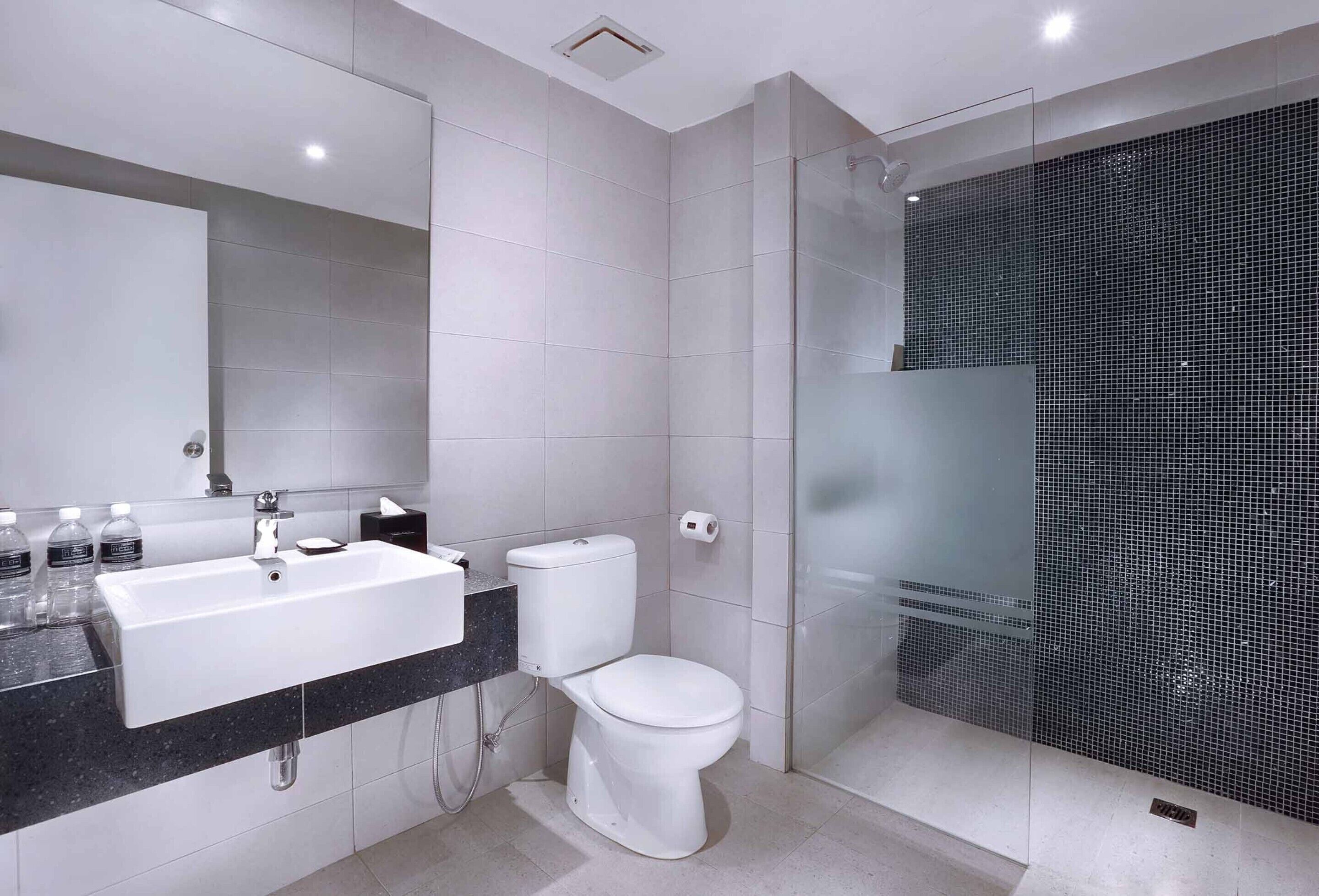 A modern bathroom with a white sink, toilet, and glass-enclosed shower.
