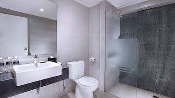 A modern bathroom with a white sink, toilet, and glass-enclosed shower.