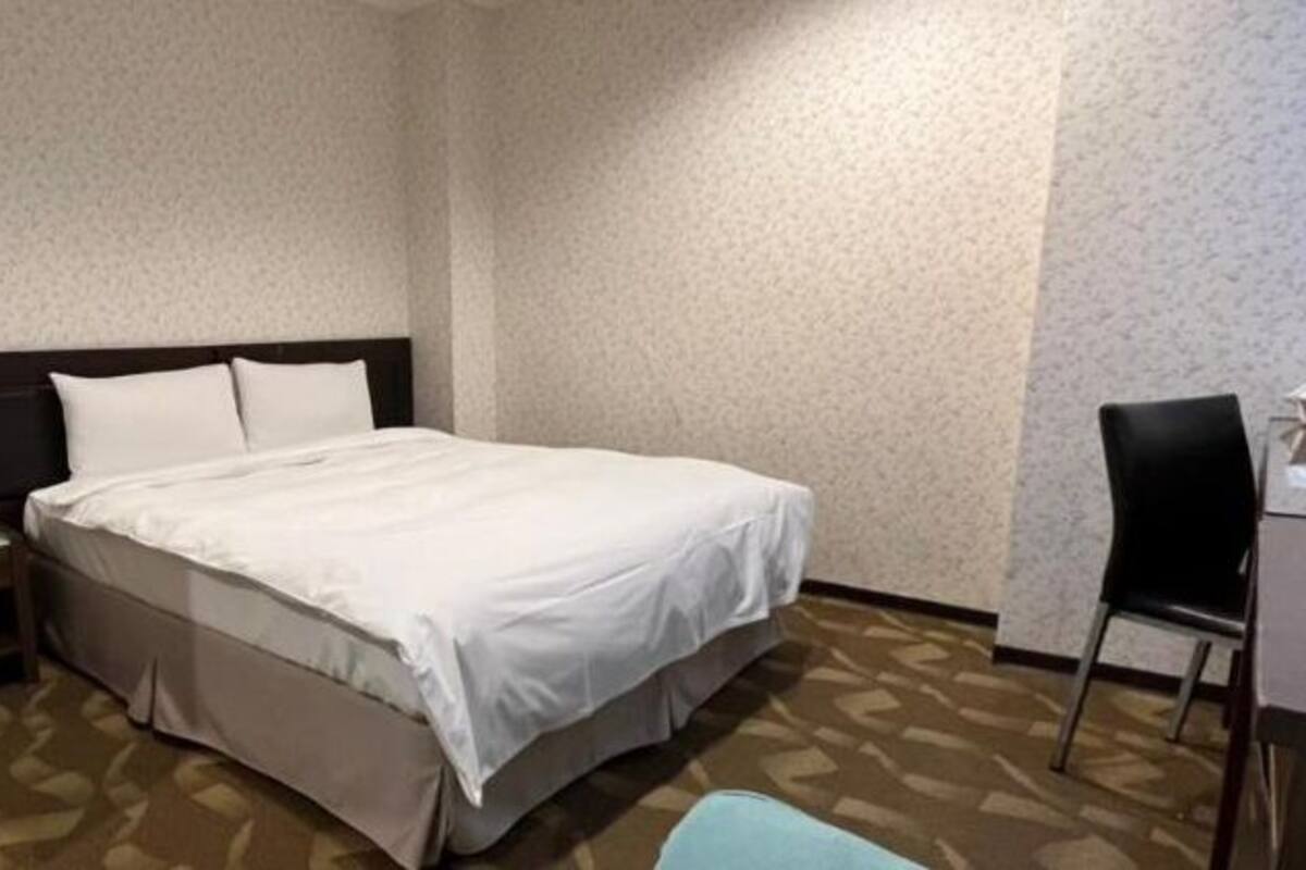 A hotel room with a bed, a desk, and a chair.