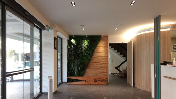 A modern reception area with a wooden staircase, a green wall, and a glass door leading outside. - Trust Hotel (Tainan)
