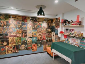 Um quarto com uma parede coberta de posters de filmes, uma mesa com toalha de mesa verde e prateleiras com diversos objetos.