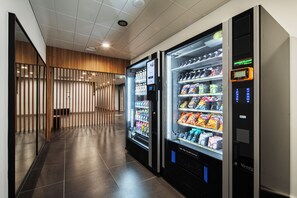 A corridor with vending machines, wooden slats, and a tiled floor.